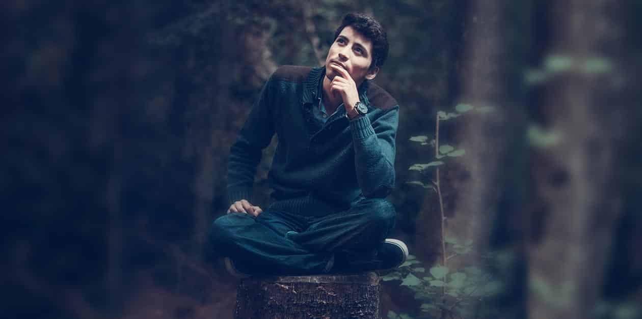 Photo of man sitting alone in a forest.